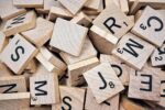 A pile of wooden scrabble tiles showing different letters