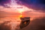 A white rowboat on body of water at sunrise